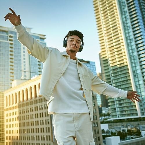 Man wearing headphones with arms outstretched in cityscape